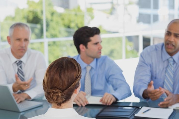 Four colleagues in discussion around a glass meeting table