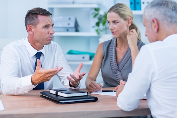 Three people in conversation across an office table
