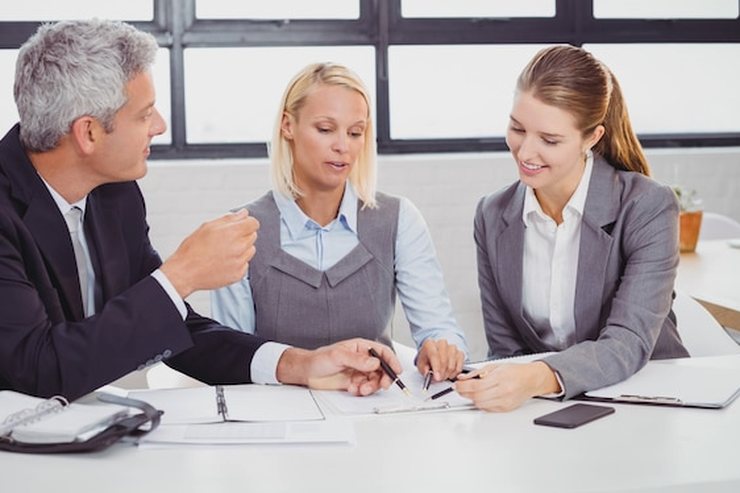 Three people reviewing a document together at an office table