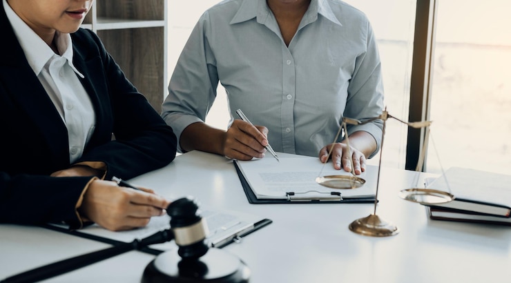 Two people at a desk with a gavel and scales in the foreground